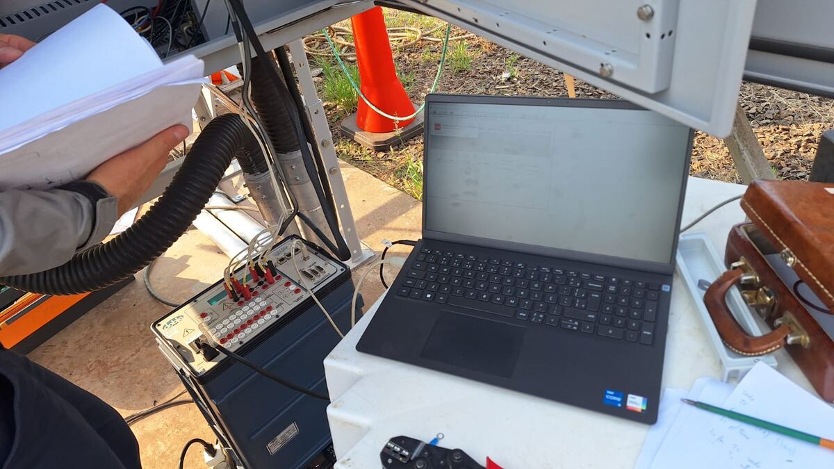 Técnico da PROINT com notebook e maleta de ensaios elétricos conectada a equipamento de subestação
